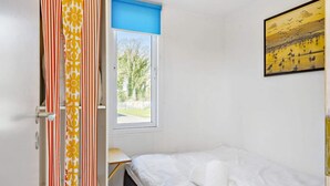 A bedroom with a bed, a window with a view of trees, and a painting on the wall. - 4 Person Holiday Park Home in Krusa (Krusaa)