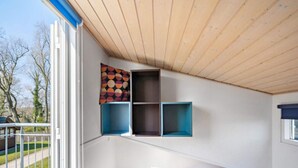 A bedroom with a sloped ceiling, a bed, and built-in shelving with colorful and dark blue storage boxes. - 4 Person Holiday Park Home in Krusa (Krusaa)
