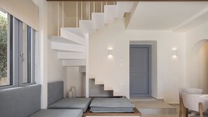 A modern interior with a staircase, grey sofas, a wooden chair, and a grey door. - Villa Seyian-Charming 3 bedroom villa-Private Pool (CHANIA)