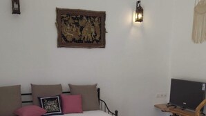 Une pièce confortable avec un lit, une petite table ronde, un tapis décoratif, un téléviseur et des lampes fixées au mur.