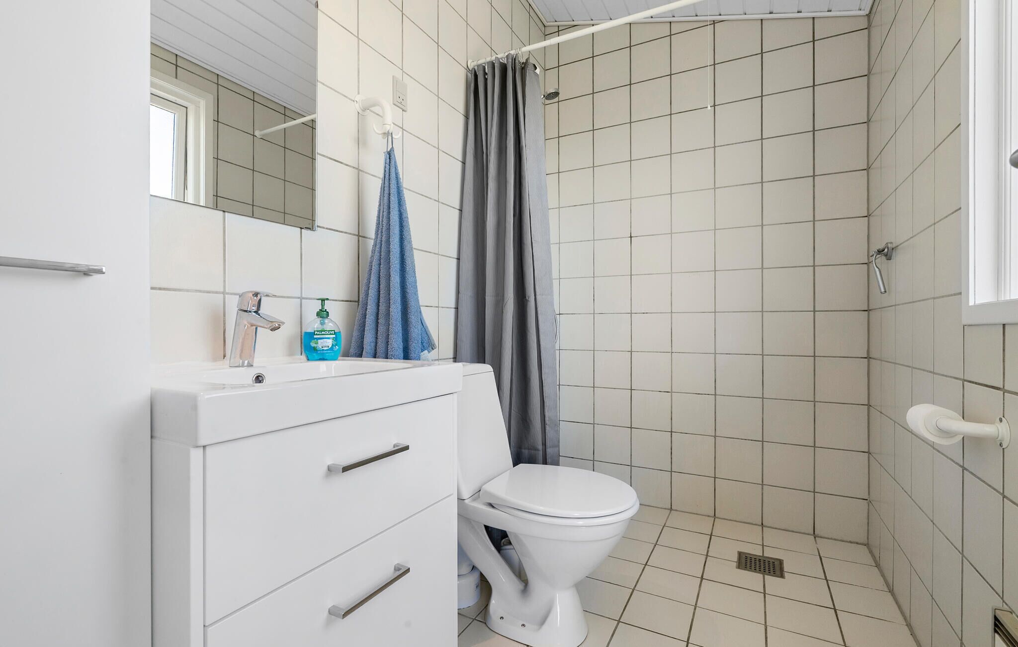 Et badeværelse med en hvid vask, toilet og en bruser med gardin.