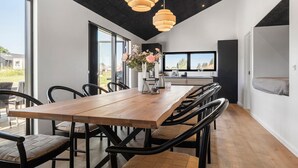 Un espace de salle à manger moderne avec une table en bois, des chaises noires et des luminaires suspendus.