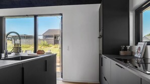 Une cuisine moderne dotée d’une grande fenêtre, d’un évier encastré et offrant une vue sur une maison à l’extérieur.