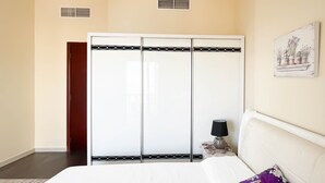 A bedroom with a bed, a wardrobe, a nightstand, and a wall-mounted lamp. - Peaceful Lagoon View l 1BR in RAK With Balcony (Ras Al Khaimah)