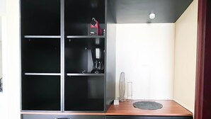 A modern kitchen with black cabinets, a coffee maker, and a wooden countertop. - Peaceful Lagoon View l 1BR in RAK With Balcony (Ras Al Khaimah)