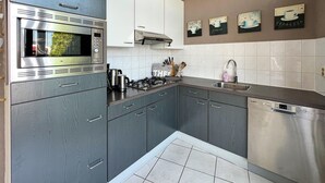 A modern kitchen with grey cabinets, a stainless steel microwave, a Bosch dishwasher, and a sink. - 2 bedroom lovely home in Lemmer (Lemmer)