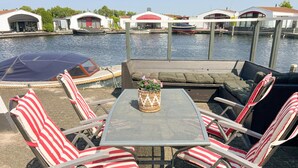 A patio with a table and chairs, a small garden table with flowers, and a view of boats on the water. - 2 bedroom lovely home in Lemmer (Lemmer)