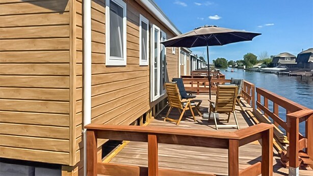 Eine Holzterrasse mit Gartenmöbeln und Blick auf einen Fluss.