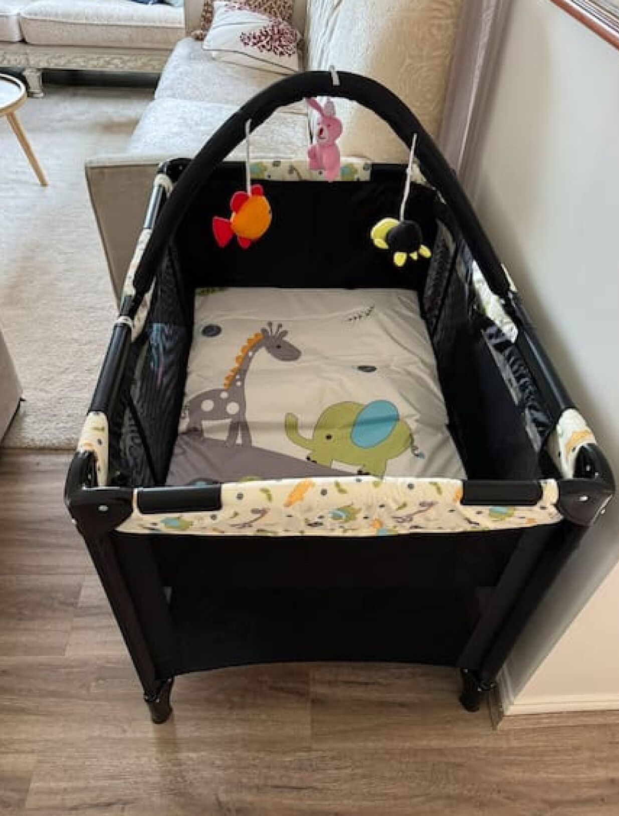 A black baby crib with a patterned mattress and a giraffe design.