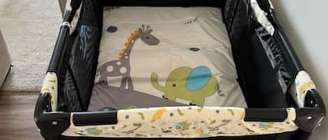 A black baby crib with a patterned mattress and a giraffe design.