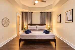 Ein Hotelzimmer mit einem großen Bett, zwei Nachttischlampen, einem Deckenventilator und Kunstwerken an den Wänden.