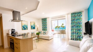 Un espacio habitable moderno con cocina, comedor y zona de estar, destacando un amplio ventanal con vistas.