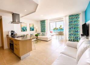 A modern living space with a kitchen, dining area, and seating area, featuring a large window with a view. - Marbella | 120 M2• Beachfront • Pool • FastWiFi (Juan Dolio)