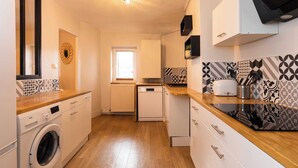 Una cucina compatta con lavatrice, lavastoviglie e un piano lavoro con un tostapane.