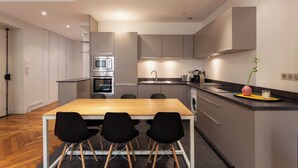 Una cocina moderna con una isla central, electrodomésticos integrados y un comedor con cuatro sillas.