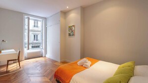 Un dormitorio con cama, escritorio y silla.