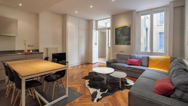 Un apartamento moderno con comedor, sofá y un amplio ventanal.