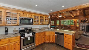 A kitchen with wooden cabinets, a microwave, stove, and a dishwasher. - Single-Story! Pet Friendly! Hot Tub! Pool Table! (Big Bear City)