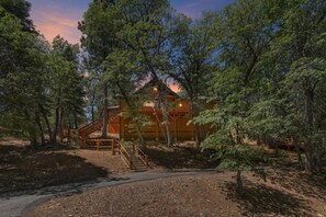 A cabin surrounded by trees with a wooden staircase leading to the entrance. - PET FRIENDLY! HOT TUB! Single Story!  Pool Table! (Big Bear City)
