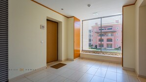 Une chambre d’hôtel dotée d’une grande fenêtre, d’une porte en bois et d’un revêtement de sol carrelé.