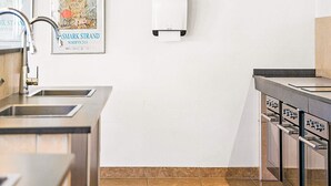 Een moderne keuken met roestvrijstalen apparatuur, een inbouwoven en een wandbevestigde papieren handdoekdispenser.