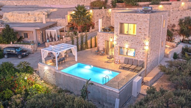 A two-story stone building with a swimming pool, outdoor seating, and a car parked nearby. - Koukis Villa With Sea View (Kissamos)