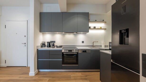 A modern kitchen with a built-in oven, a coffee maker, and a refrigerator.