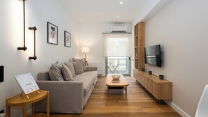 A modern living room with a sofa, a coffee table, a TV mounted on the wall, and a wooden cabinet.
