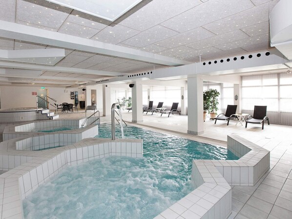 A large indoor swimming pool with multiple levels and a sunlit area with lounge chairs.