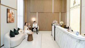 Un espace d’accueil d’hôtel au design moderne, comprenant un comptoir d’accueil, un coin salon et une grande œuvre d’art encadrée au mur.