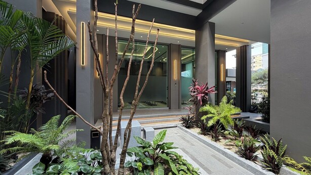 Un bâtiment moderne doté d’un escalier, de plantes d’intérieur et d’une entrée en verre.