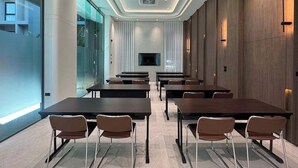 Une salle de conférence moderne avec des murs en verre, un téléviseur à écran plat et un luminaire central au plafond.