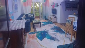 A living room with a sofa, coffee table, and a patterned rug. - Cozy apartment close to the Giza Pyramids' (El Sheikh Zayed City)
