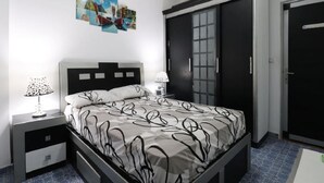 A bedroom with a bed, two bedside tables, a wardrobe, and a door. - Cozy apartment close to the Giza Pyramids' (El Sheikh Zayed City)