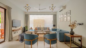Uma sala de estar moderna com sofá, cadeiras, mesa de centro e televisão.