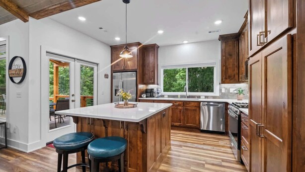 Una cocina moderna con armarios de madera, una isla central, un refrigerador de acero inoxidable y un lavavajillas.