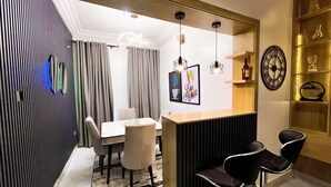 A modern dining area with a wooden bar, a round table, and black chairs. - Luxury 3BR Ensuite Apartment 24/7 Power Fast WiFi Secure Estate Ikeja Lagos (Ikeja)