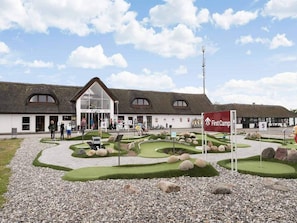A building with a thatched roof, a reception area, and a landscaped garden with a golf course model.