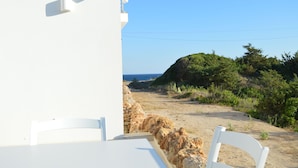 Un bâtiment blanc avec un mur en pierre et une vue sur la mer.