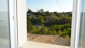 Une vue depuis un balcon, avec un ciel dégagé, une vég étation luxuriante et un bâtiment situé au loin.