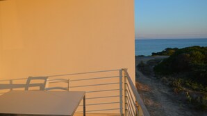 A balcony with a table and chairs overlooking a beach and ocean. - Myrtle studio apartment with sea view terrace, in the dunes 20m from free beach (Monaco Mirante)