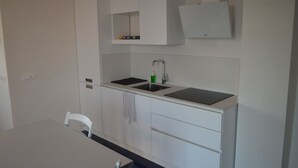 A modern kitchen with white cabinetry, a double sink, and a countertop. - Myrtle studio apartment with sea view terrace, in the dunes 20m from free beach (Monaco Mirante)