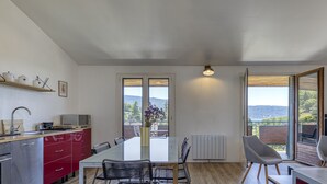 Eine moderne Küche mit Essbereich, großen Fenstern und Blick ins Freie.