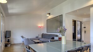 Ein modernes Wohnzimmer mit einem Glastisch, einem grauen Sofa und einem großen Spiegel.