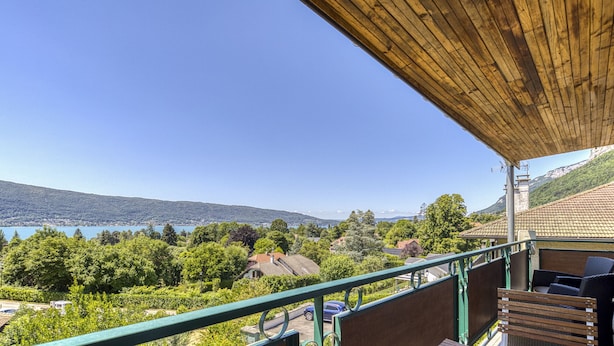 Ein Balkon mit Holzdach und Blick auf eine malerische Landschaft mit Bäumen und einem Gewässer.