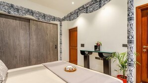 Una habitación de hotel con una cama, un armario de madera, un lavamanos pequeño y una planta en maceta.