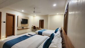 Habitación de hotel con dos camas, televisión, escritorio y silla.