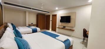 Habitación de hotel con dos camas, un televisor en la pared, un escritorio y una silla.