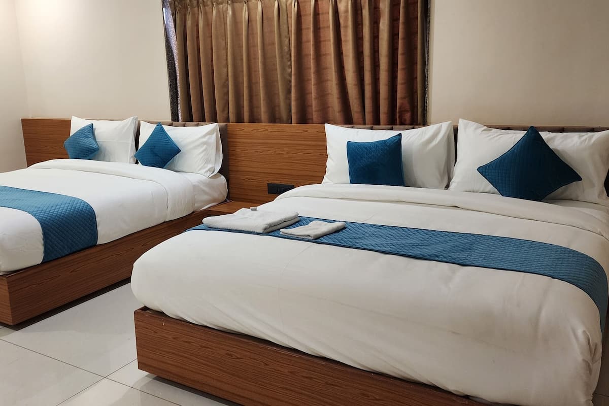 Ein Hotelzimmer mit zwei Einzelbetten, jeweils mit einem Holz-Kopfteil, weißer Bettwäsche und blauen Akzenten.