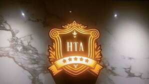 Un logotipo con las letras 'HTA' sobre una pared de mármol.